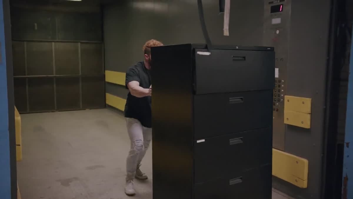 Recycle Boston crew member carrying an item through an office hallway